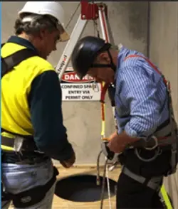 two men working in a confined space taking safety precautions two men working in a confined space taking safety precautions